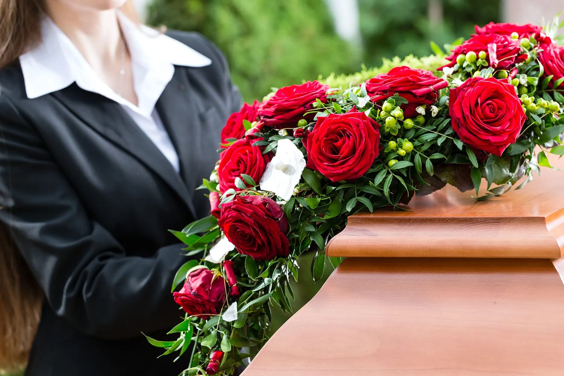 Dessus de cercueil en roses rouges posé sur un cercueil en bois